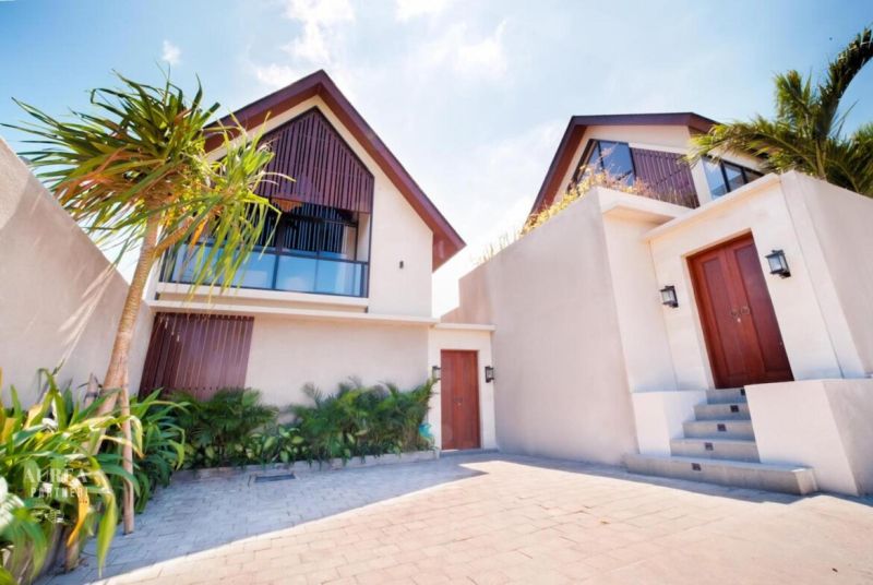 Villa in Bali with a garden and palm trees, modern architecture, stone pathway.