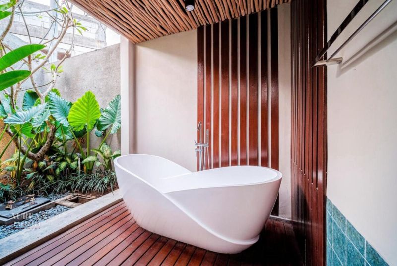 White bathroom in a villa with leafy plants and wood-patterned floor.