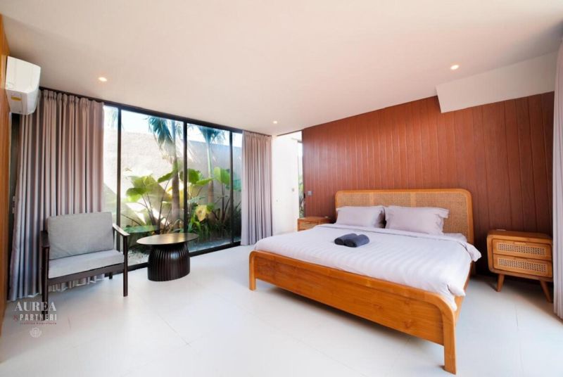 A bedroom in a villa with wooden decor, a bed, and large windows.