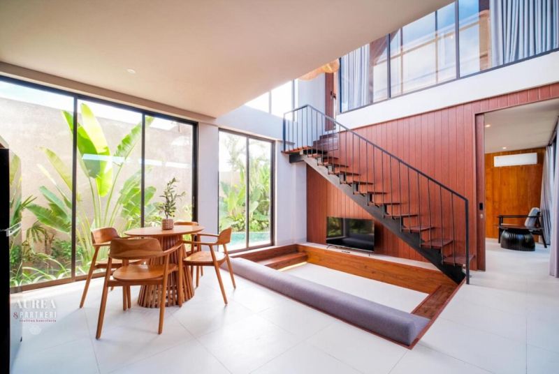 Space in the Villa with large windows, a wooden staircase, and a dining table.