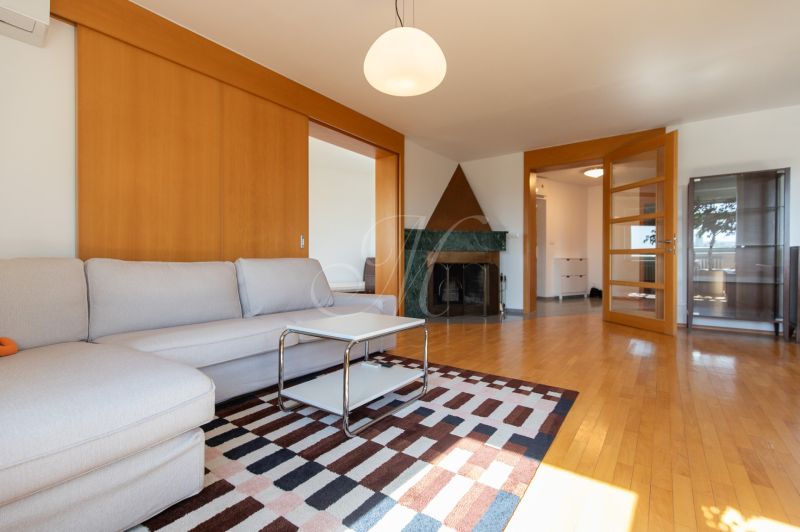 Living room with a sofa, coffee table, fireplace, and wooden decor flooring in a 4-room apartment.