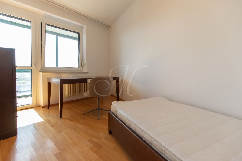 A room with a bed, a table, and a floor with a wooden decor in a 4-room apartment.