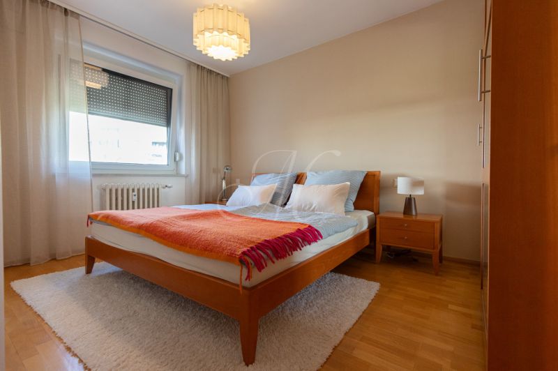 Bedroom with a double bed, nightstand, and wood-patterned flooring in a 4-room apartment.