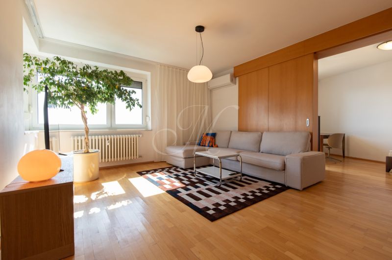 Living room in a 4-room apartment with a sofa, carpet, and wood-patterned flooring.