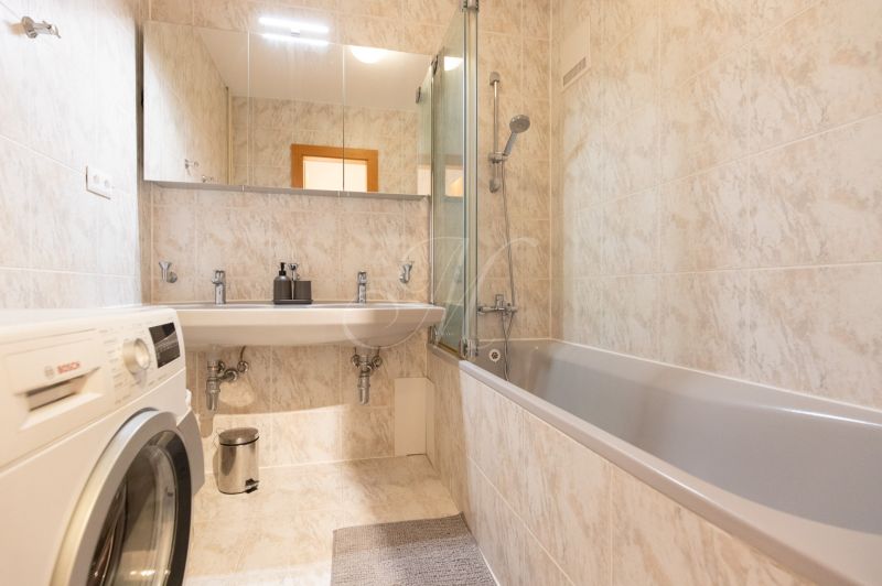 A bathroom with a bathtub, a mirror, and a washing machine in a 4-room apartment.