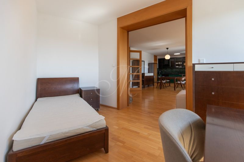 Bedroom with a bed and a dresser, connected to the kitchen, floor with a wooden decor.