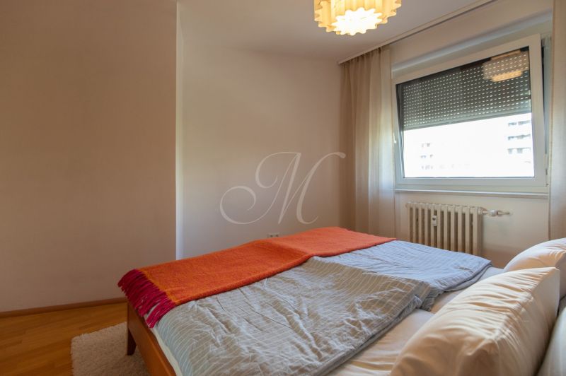 A bedroom in a 4-room apartment with a bed and a floor with a wooden decor.