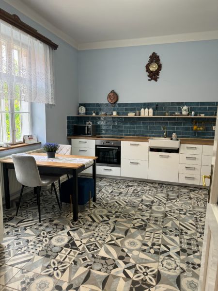 A kitchen in a family house with blue tiles and patterned flooring.