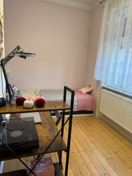 A room in a family house with a bed, a shelf, and a floor with a wooden decor.