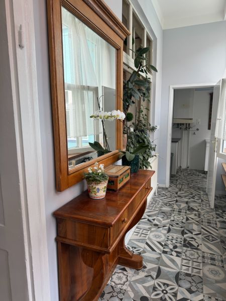 Wooden dresser with flowers and a mirror, designed tiles on the floor.
