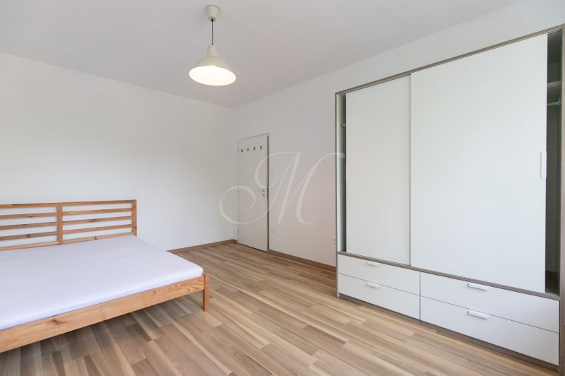 A bedroom in a 3-room apartment with a bed, cabinets, and a floor with a wooden decor.