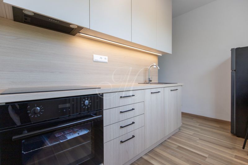 A kitchen in a 3-room apartment with a wooden decor, built-in oven, and refrigerator.