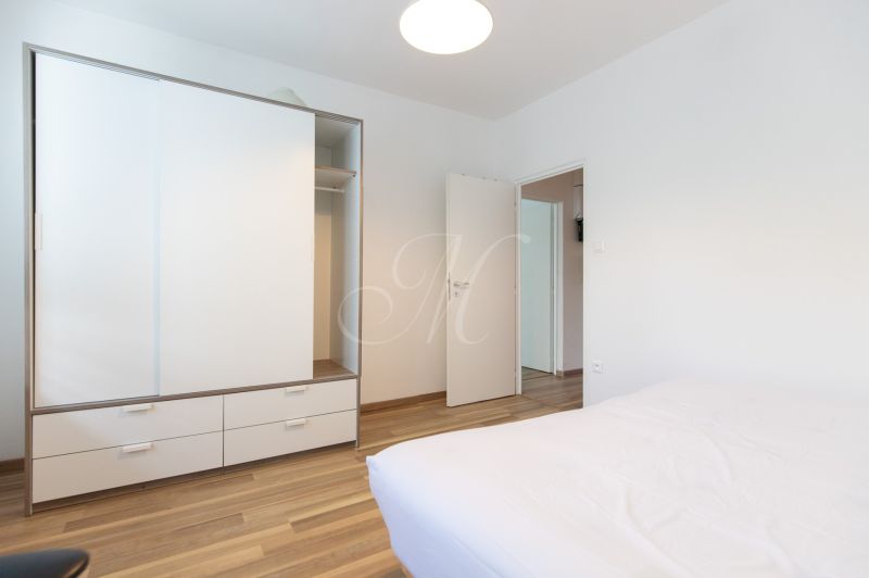 A bedroom in a 3-room apartment with a white wardrobe and a floor with a wooden decor.