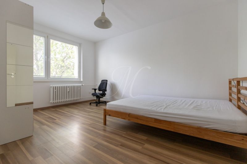 Bright bedroom with a bed and an office chair, floor with wood decor.
