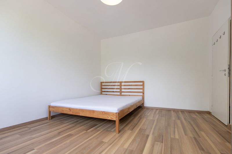 A bedroom with a bed, a floor with a wooden decor, in a three-room apartment.