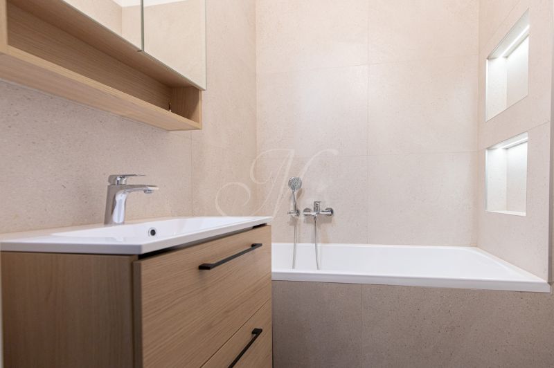 Bathroom in a 3-room apartment with a bathtub and a cabinet with a wooden decor.