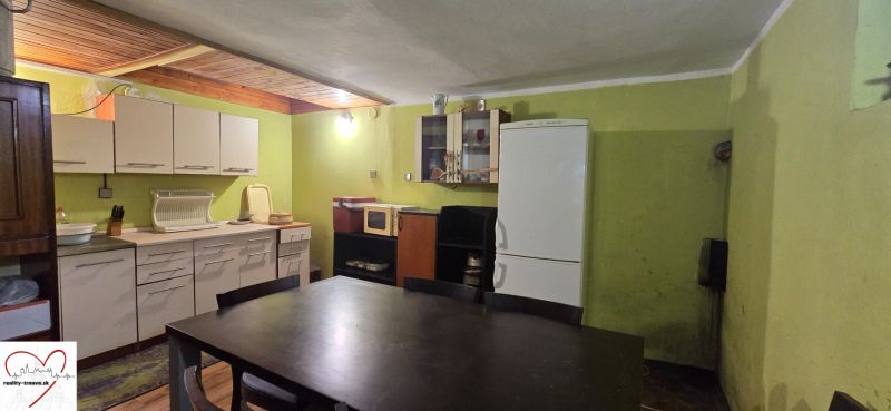 A kitchen in a cottage with a wooden decor floor, simple furniture, and appliances.