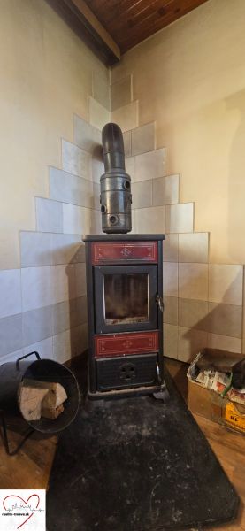 A stove in the corner of a cabin with a wooden decor floor and tiled cladding.