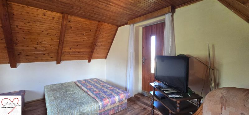 Interior of a cabin with a bed, television, and a floor with wooden decor.