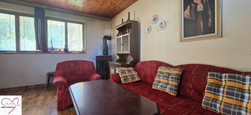 Living room in a cottage with a red sofa, wood-patterned floor, and a painting on the wall.