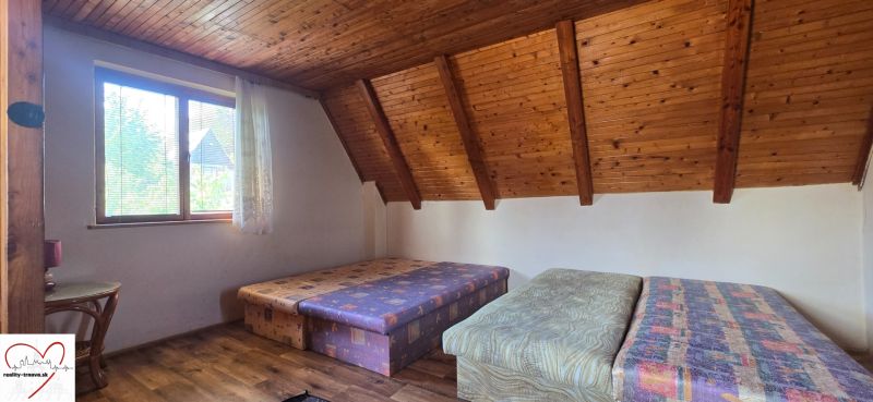 A room in a cabin with double beds, a wooden ceiling, and a floor with a wooden decor.