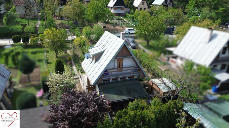 A cottage in Nové Vinohrady in Suchá nad Parnou surrounded by greenery and neighboring cottages.
