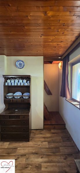 The interior of the cabin with a wood-patterned floor, wooden ceiling, and porcelain dishes.