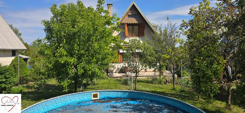 A cottage in Suchá nad Parnou, Nové Vinohrady, surrounded by greenery and a swimming pool.