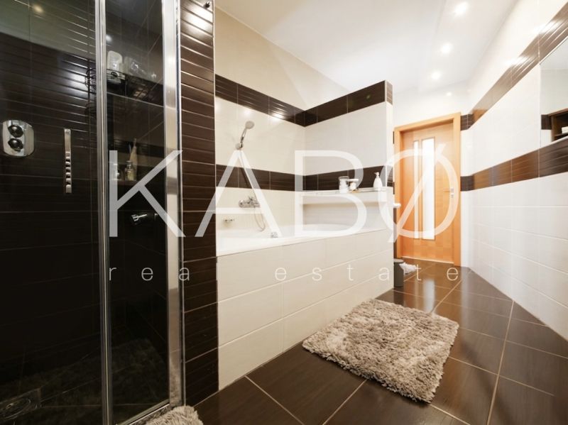 A bathroom in a family house with a bathtub, a shower corner, and tiles with a wooden decor.