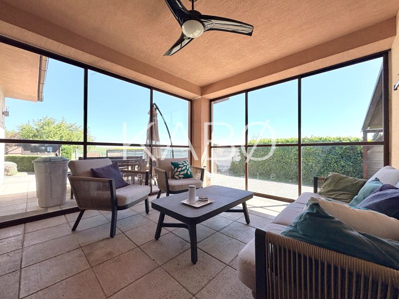 A glazed terrace with comfortable seating in a family house.