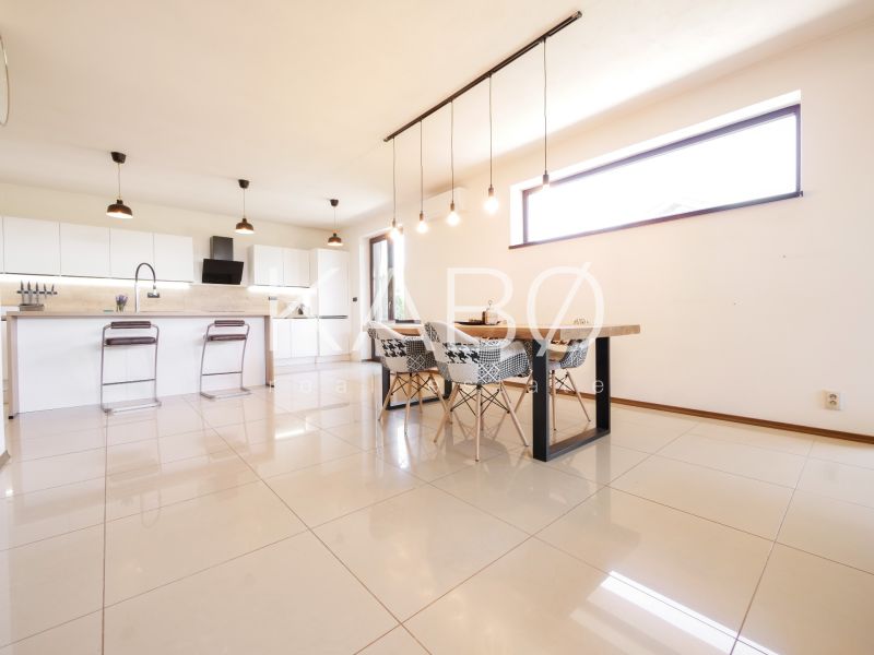 Kitchen in a family house with a dining table, bar stools, and light tiles.