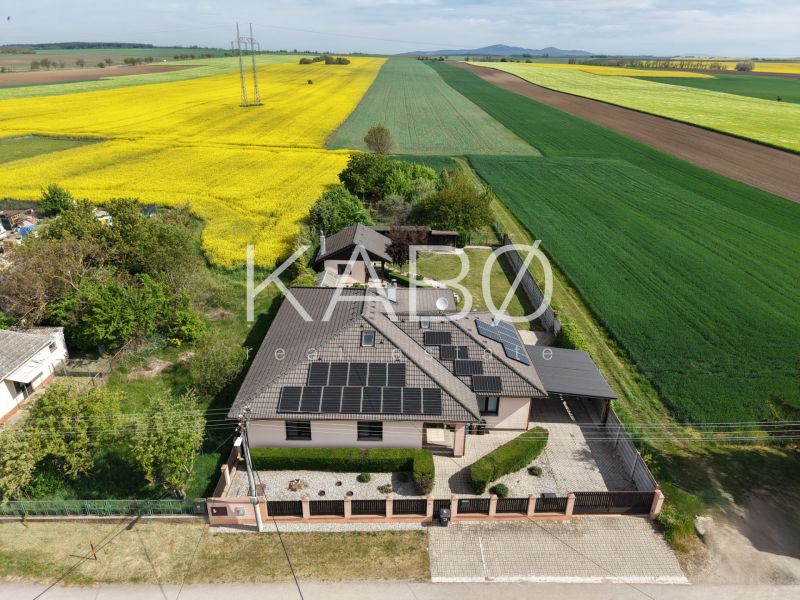 A family house on Močenská Street in Cabaj-Čápor, surrounded by a field of yellow rapeseed flowers.