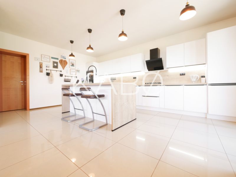 A kitchen in a family house with white cabinets, a bar counter, and tiles.