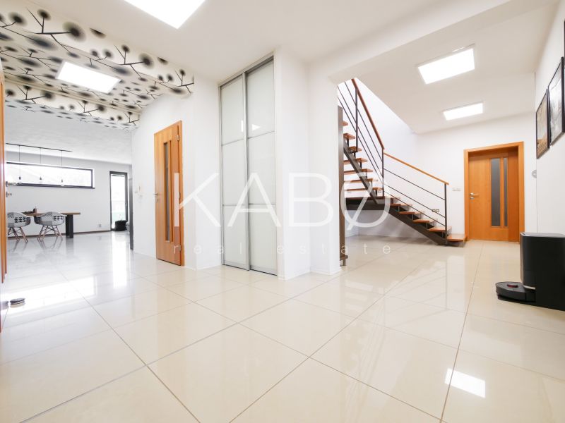 Interior of a family house with an open staircase, large-format tiles, and a decorative ceiling.