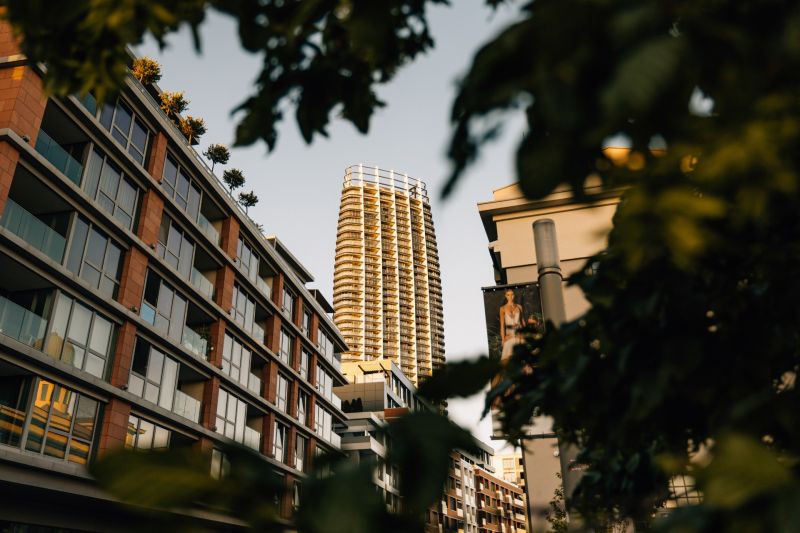 A high-rise building in the background of a street with greenery and residential units in Bratislava.