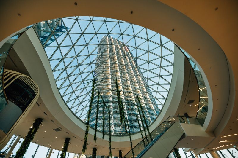 A spacious atrium with a glass roof and a tall building in the background.