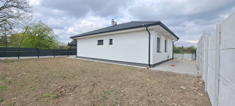 A family house in Selice with a garden and a concrete fence in cloudy weather.