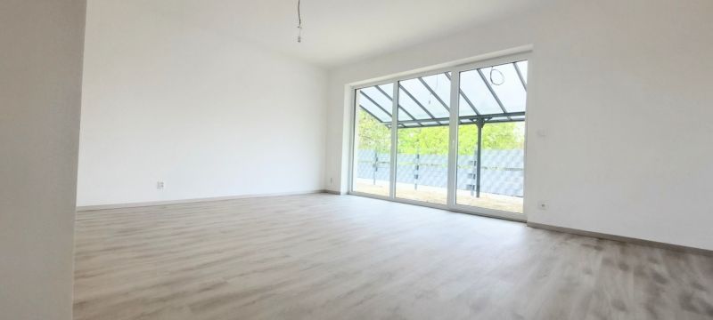 A spacious room in a family house with a wooden decor floor and large glazing.