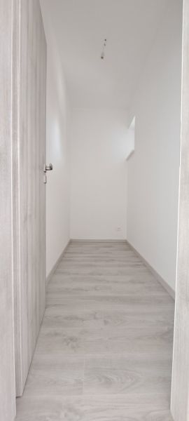 A narrow hallway in a family house with a wooden decor floor and white walls.