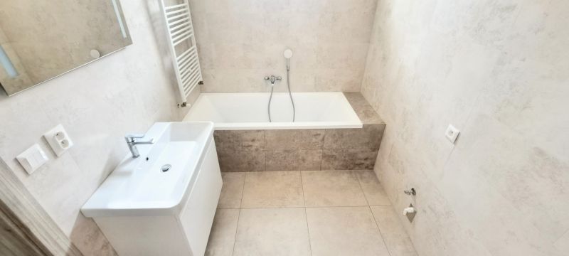 Bathroom with a bathtub, sink, and ladder radiator in a family house.