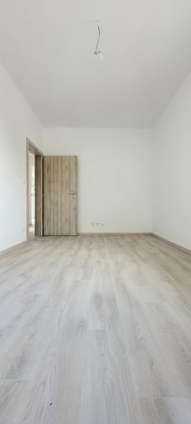 A room with a wooden decor floor and wooden doors in a family house.