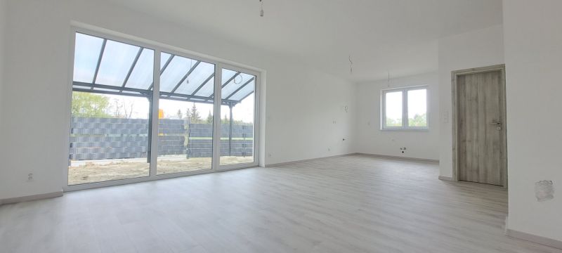 A spacious interior of a family house with large windows and a wooden decor floor.