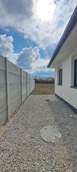 A family house in Selice with a concrete fence and gravel paving in the yard.