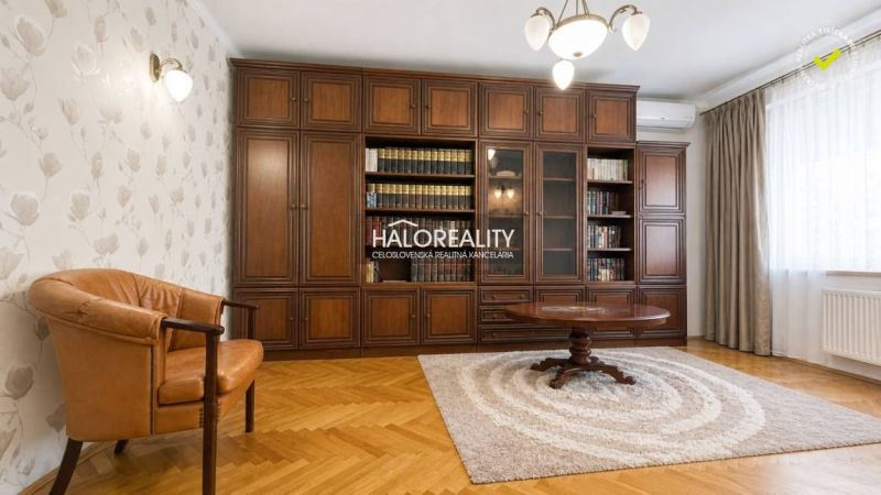 Living room in a 3-room apartment with a bookshelf, an armchair, and a wooden decor floor.