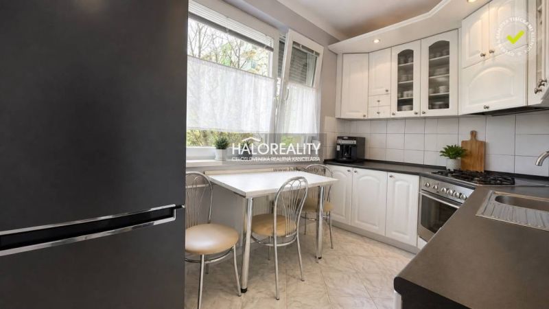 A kitchen in a 3-room apartment with white cabinets, a table, and four chairs.