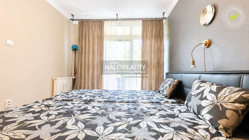 A bedroom in a 3-room apartment with floral patterned bed linen and curtains.
