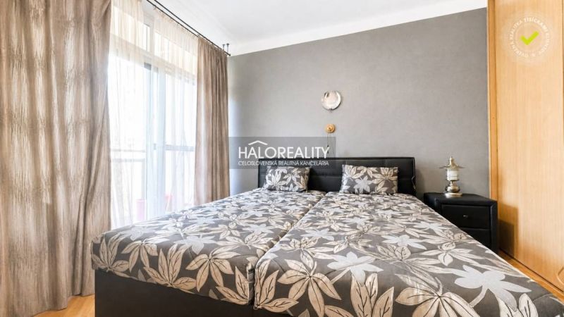 Bedroom with patterned bedding in a 3-room apartment, next to a wardrobe and a lamp.