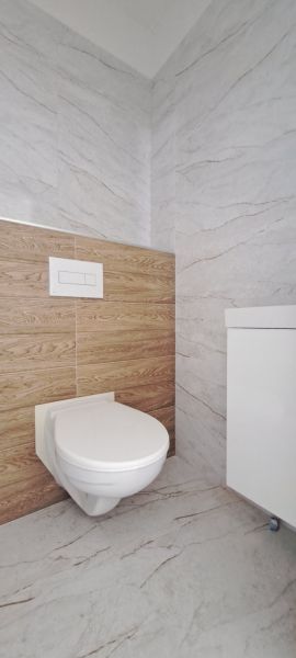 A toilet in the bathroom of a family house with marble and wooden tiles.