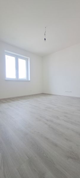 An empty room with white walls and a floor with a wooden decor in a family house.
