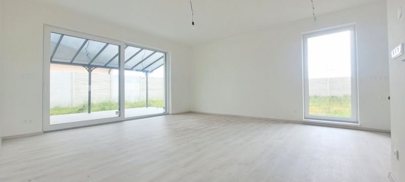 A spacious room with large windows and a wooden decor floor in a family house.